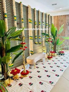 a table with flowers and candles on it in front of a wall decorated with plants