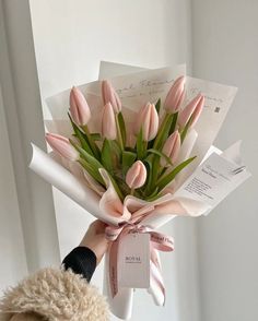 a bouquet of pink tulips wrapped in white paper