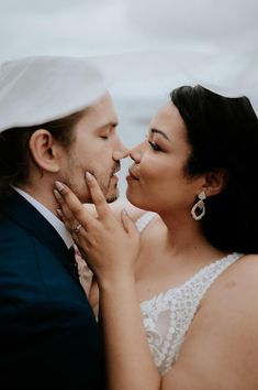 a bride and groom kissing each other in front of the ocean