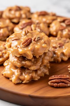 a wooden plate topped with cookies covered in caramel glaze and pecans on top of it