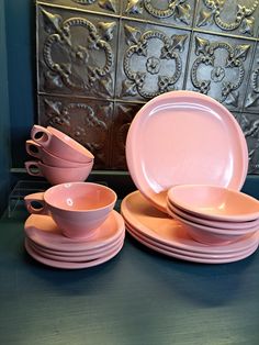 pink dishes and cups are stacked on top of each other