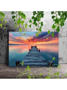 a wooden dock in the middle of water at sunset