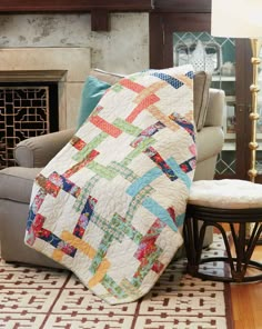 a living room with a couch, chair and blanket on the floor in front of a fireplace