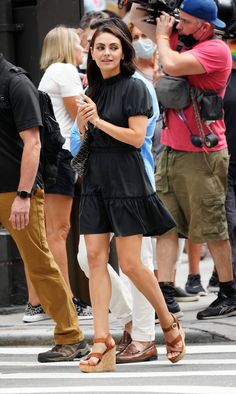 a woman in black dress walking across a street