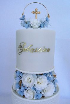 a three tiered cake with blue flowers and a cross on top