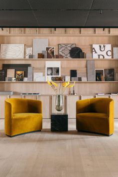 two yellow chairs sitting next to each other in front of a book shelf filled with books