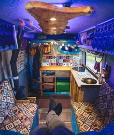 the interior of an rv with blue walls and colorful tiles on the floor, while someone's feet are propped up in front of the stove