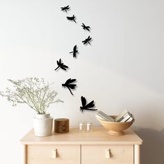 a wooden table topped with a vase filled with flowers next to a wall mounted clock