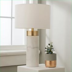 a white table lamp sitting next to a potted plant