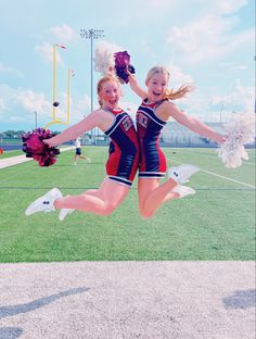 two cheerleaders are jumping in the air