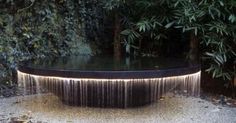 an outdoor fountain in the middle of a garden with water flowing from it's sides