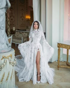 a woman in a white wedding dress standing next to a table with a statue on it