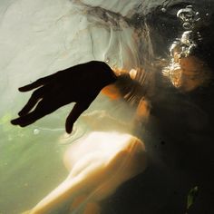 a person swimming in the water with their hand up