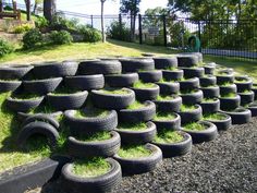 a pile of old tires sitting on top of a gravel road next to a lush green field