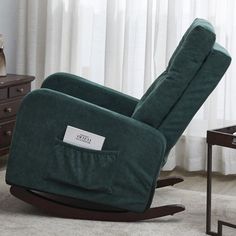 a green recliner chair sitting on top of a rug next to a wooden table