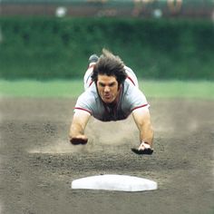 a baseball player dives into the dirt to catch a ball during a game,