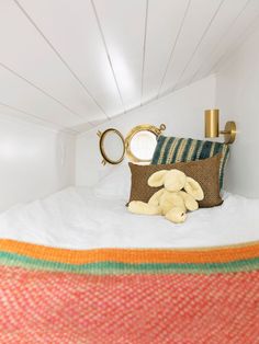 there is a stuffed animal that is on the bed in this small room with white walls