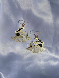 Shimmery black  and white resin in a brass moon shaped setting. Golden hypoallergenic earring hooks are made of 925 silver-plated copper. Each piece is handmade and is created by carefully pouring and mixing resin into each individual section. This tedious process leads to beautiful vibrant colors that imitate a stained glass look in a much more durable and lightweight way. Every piece is naturally unique as it is impossible to maintain the pigment to resin ratio, leading to large variations of Black Celestial Earrings For Gift, Black Metal Moon Shaped Jewelry, Black Metal Moon-shaped Jewelry, Handmade Black Moon-shaped Earrings, Handmade Black Moon Earrings, White Handmade Moon-shaped Earrings, Black Crescent Moon Charm Earrings, Black Moon Phase Earrings, Black Moon-shaped Earrings For Gift