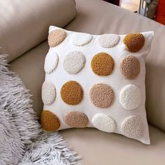 a white pillow with brown and tan circles on it next to a gray furnishing