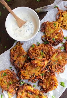 potato fritters with sour cream and parsley on parchment paper next to a bowl of ranch dressing