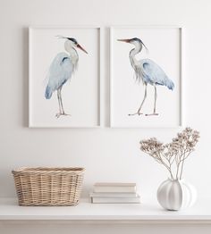 two paintings of birds are on the wall next to a basket and vase with flowers