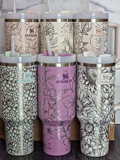 six travel mugs with floral designs on them sitting next to each other in front of a marble wall