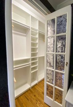 an empty walk in closet with white shelves and glass doors that lead to another room