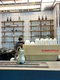 a blue and white vase sitting on top of a counter next to shelves filled with bottles