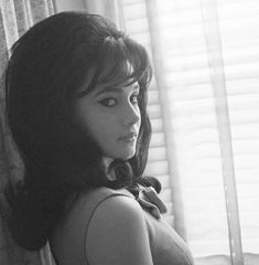 a black and white photo of a woman leaning against a wall