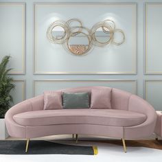 a pink couch sitting in front of a wall with gold circles on it's face