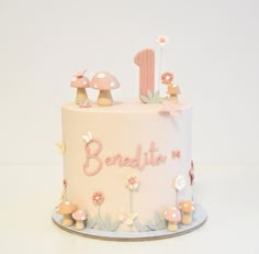 a white cake with pink decorations and the number one on it