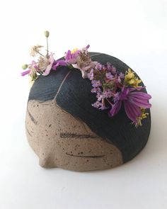 a clay head with flowers on top of it