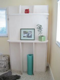 there is a shelf with pictures on it in the corner next to a cat bed