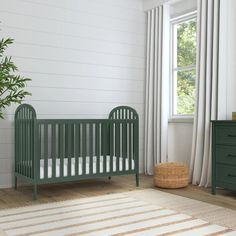 a baby's room with a green crib, dresser and small potted plant