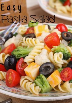 a pasta salad with tomatoes, broccoli, olives and cheese on it