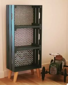 a wooden toy car sitting next to a tall bookcase with different patterns on it