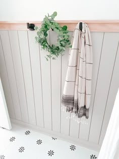 a towel hanging on the wall next to a mirror and door handle with a wreath