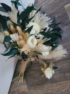 an arrangement of flowers and feathers on a wooden table