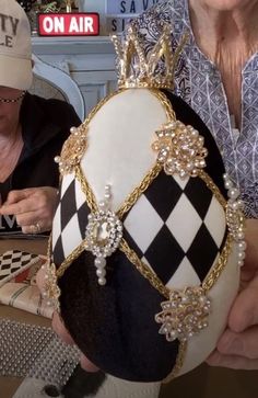 an older woman wearing a hat with pearls on it while sitting in front of a table