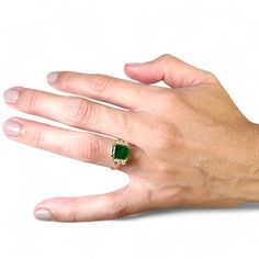 a person's hand with a ring on it and a green stone in the middle