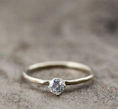 a gold ring with a single diamond on it sitting on a stone surface in front of the camera