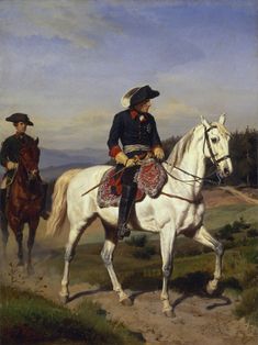 two men riding horses on a path in a field with trees and bushes behind them