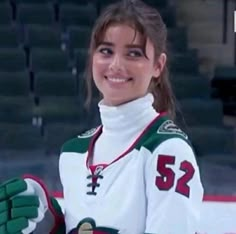 a female hockey player is smiling and holding her hands up in front of the camera