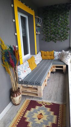 a couch made out of wooden pallets sitting on top of a floor next to a window