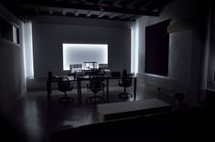 a dimly lit room with chairs and desks