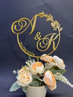 a white vase filled with flowers and a gold monogrammed cake topper