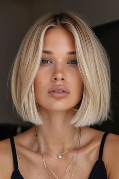 a woman with blonde hair wearing a black top and necklaces on her neck is looking at the camera