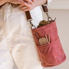 a person holding a pink bag with some knitting needles in it's back pocket