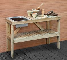 a wooden table sitting on top of a hard wood floor next to a planter