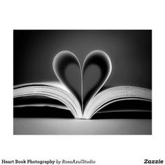 an open book with two pages in the shape of a heart on top of it